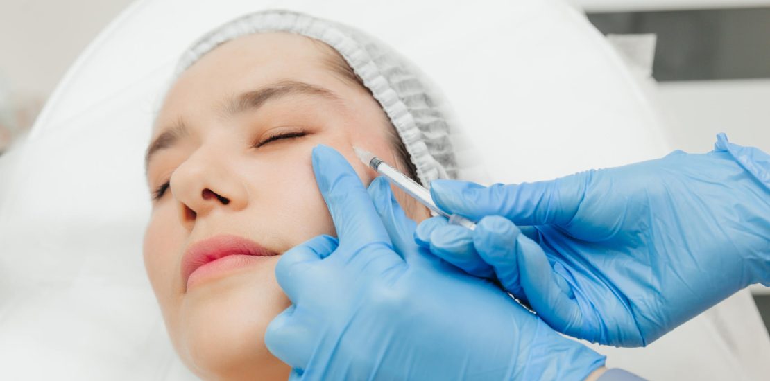 Close-up of the hands of a beautician injecting Botox into a woman's forehead. Correction of forehead and eye wrinkles with botulinum toxin.