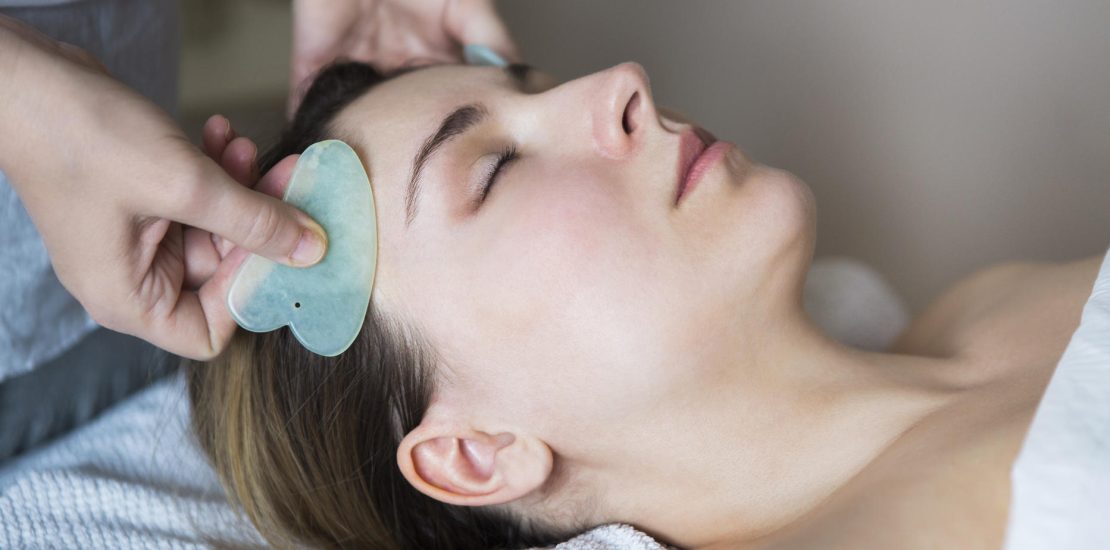 Young woman have face guasha treatment at asian beauty clinic
